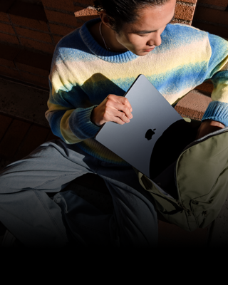 Osoba si do batohu dává 15palcový MacBook Air v temně inkoustové barvě